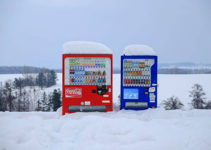 Two vending machines in Japan, standing in deep snow.